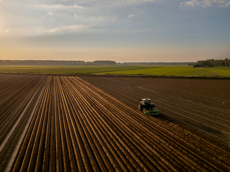 a tractor plowing a field at sunset